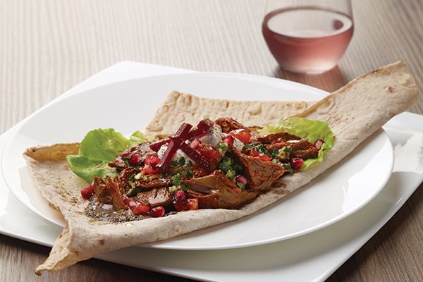 Braised Lamb Shawarma features fork-tender lamb served atop lavash bread.