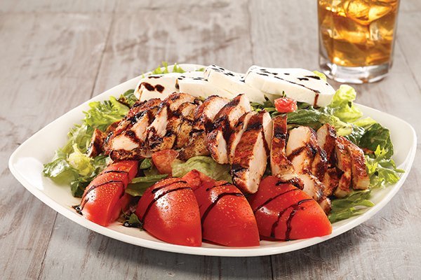Firebirds has made mindful adjustments to its meat-oriented menu to include dishes like this Sorrento Chicken Salad, where produce gets equal billing.