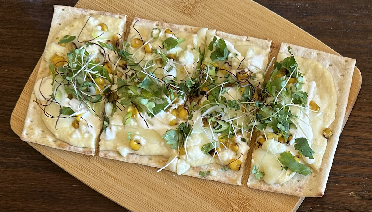 Reimagine elote as a pizza or flatbread that blends Cotija cheese and sweet white corn into a rich and creamy sauce that’s topped with fresh cilantro and microgreens.