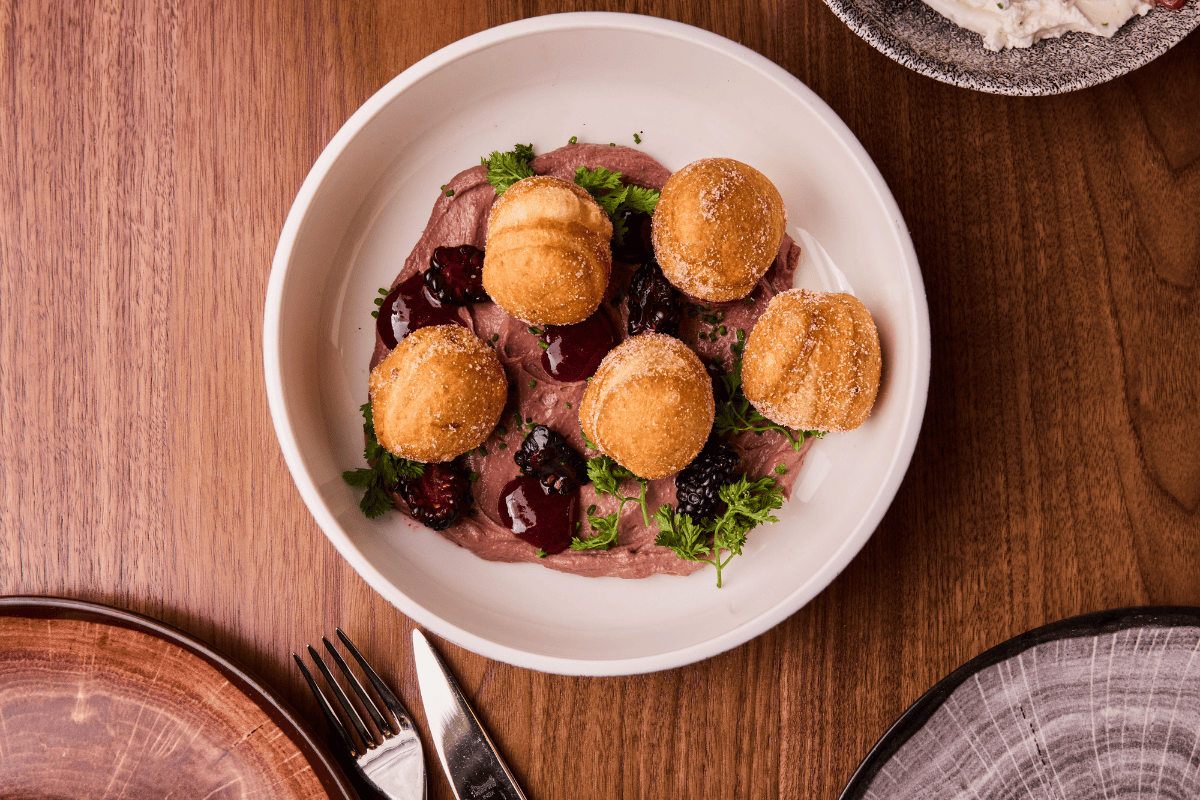 Creamy chicken liver mousse finds sweet notes and textural contrast in banana bread donuts, Espelette-spiced cherry compote and blackberries.